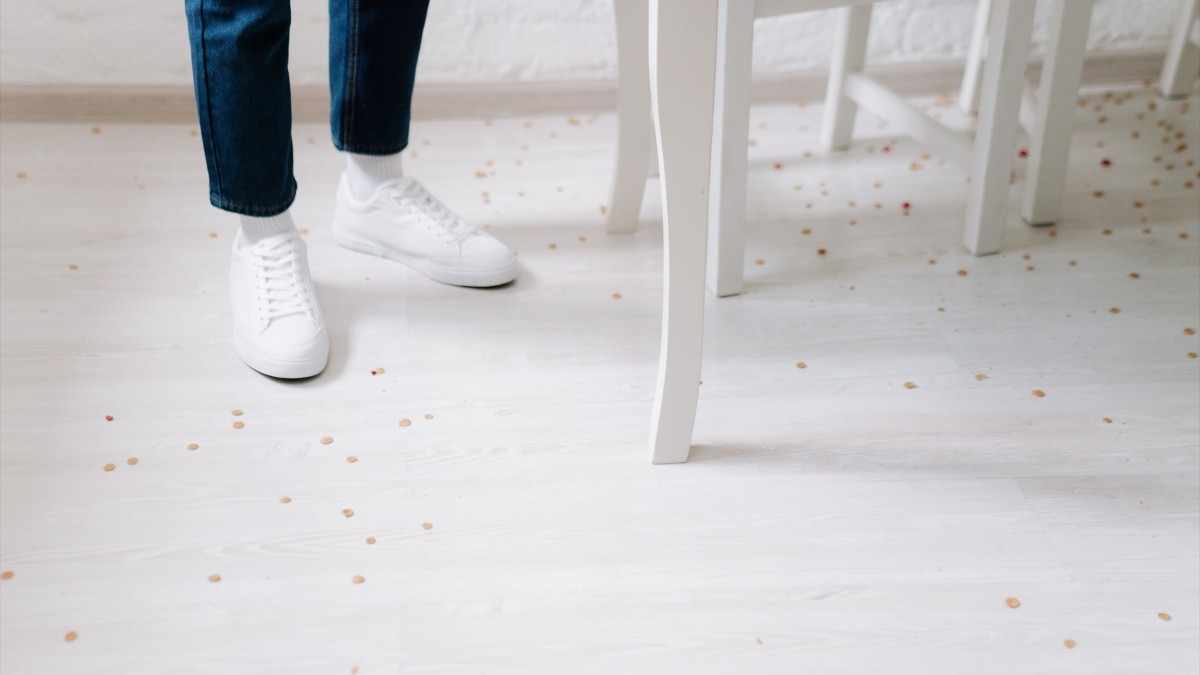 Cornflakes scattered across a floor beside an overturned white bowl.