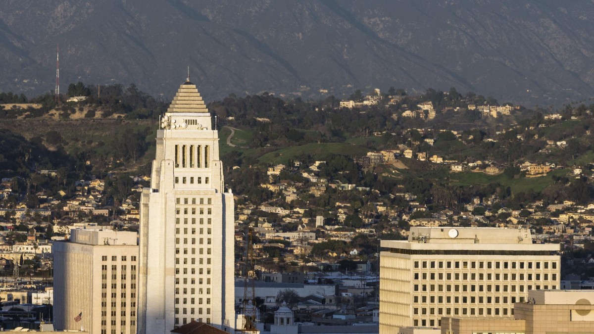 The downtown Los Angeles skyline, with the white tower of Los Angeles City Hall at the center among surrounding office buildings.