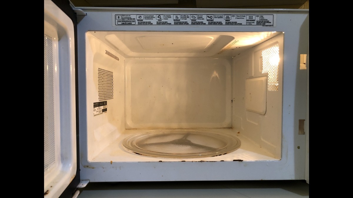 The open cooking cavity of a household microwave oven, with a glass turntable and door seal visible.