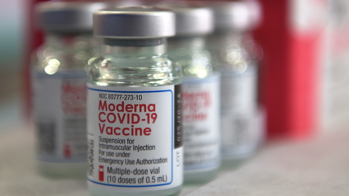 Several Moderna COVID-19 vaccine vials arranged on a table.