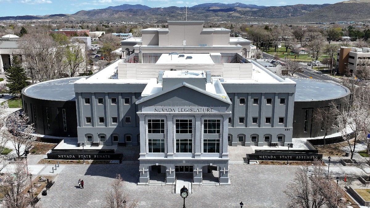 Aerial view of the Nevada Legislature building in Carson City, with the Senate and Assembly signs out front and mountains behind.