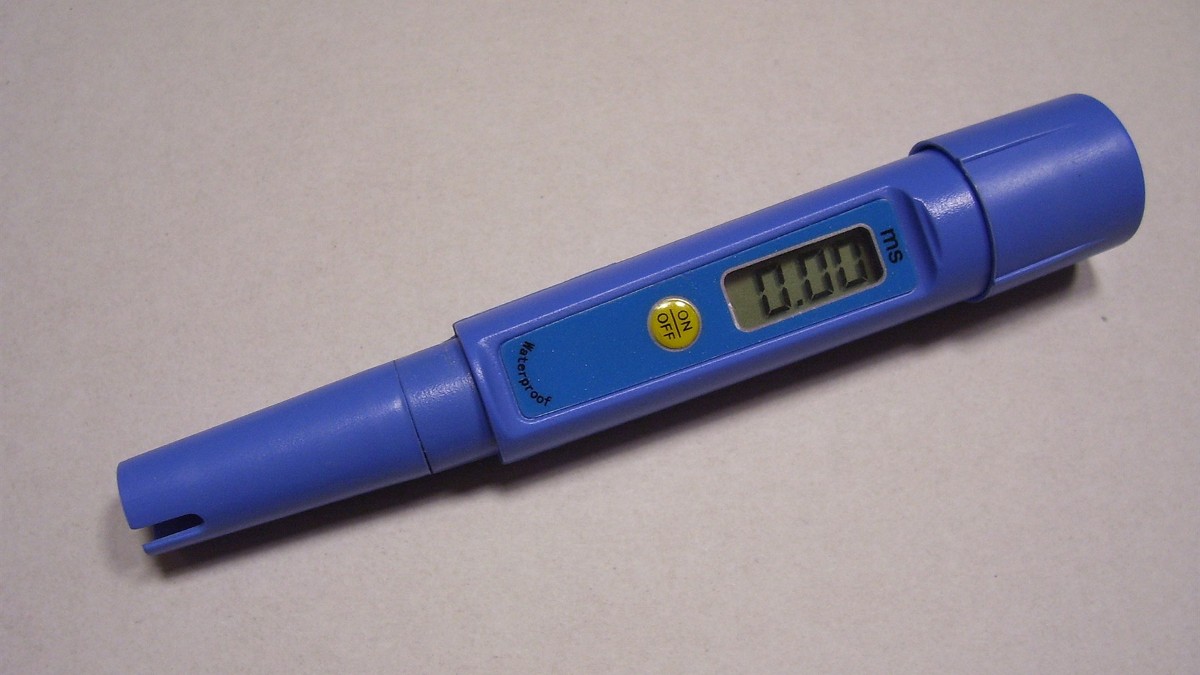 A handheld electrical conductivity meter with its probe beside a small display unit.