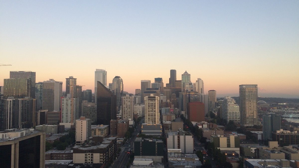Downtown Seattle's skyline of glass office towers under a cloudy sky.