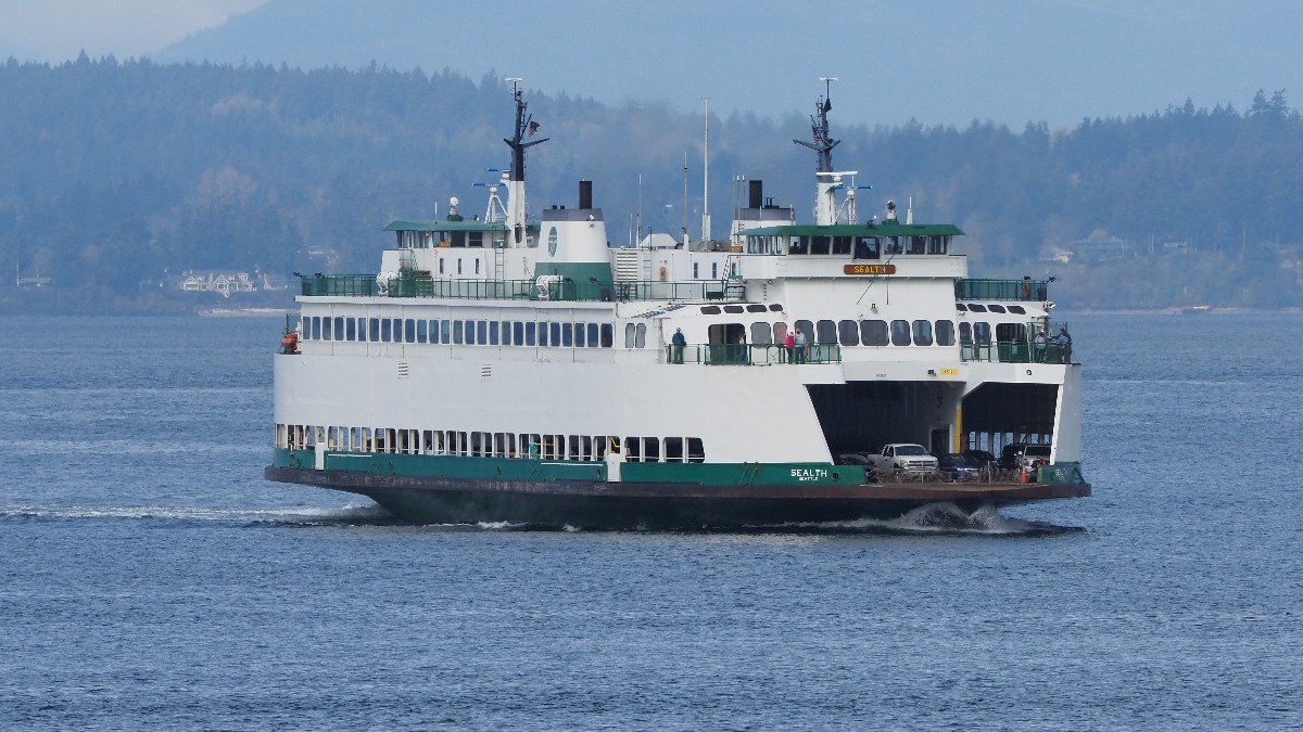 The white and green Washington State Ferries vessel MV Sealth travels across blue water near Seattle.
